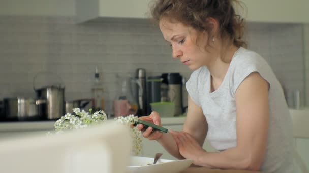 Een mooie jonge vrouw die het eten van kip Parmezaanse kaas pasta bij huis keuken — Stockvideo