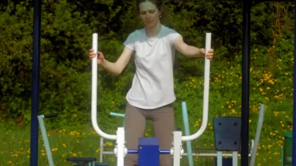 Junge Fitness-Frau macht Übungen auf der Turnhalle in einem Outdoor-Park — Stockvideo