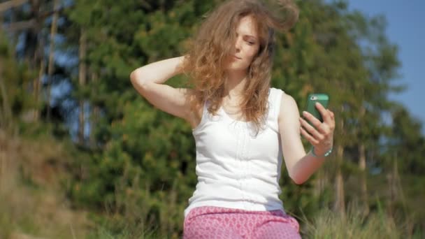 Jonge vrouw met behulp van een smartphone in een forest. Mooi meisje te typen op de telefoon in het bos. — Stockvideo