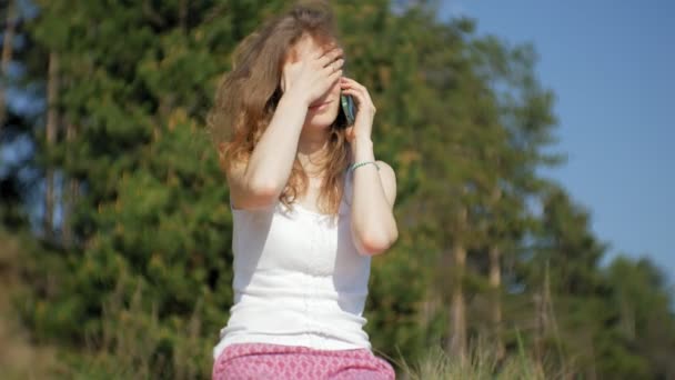 Bir ormanda bir akıllı telefon kullanan genç kadın. Güzel kız ormanda telefonda yazarak. — Stok video
