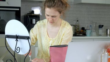 Genç güzel kadın evde bir ayna önünde makyaj.