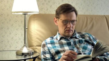 Evde yatak odasında bir kitap okuma yatakta yatan olgun adam