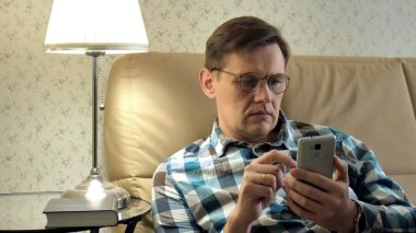 Online satın alma bir adam close-up bir telefon ve bir kredi kartı kullanan kanepede eve yaşam tarzı akıllı iş internet teknoloji banka bankacılık para tutan cep telefonu istemci closeup aygıt el alışveriş