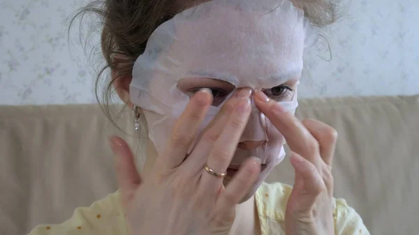 Jovem mulher fazendo máscara facial com máscara de limpeza no rosto na cozinha em casa — Fotografia de Stock