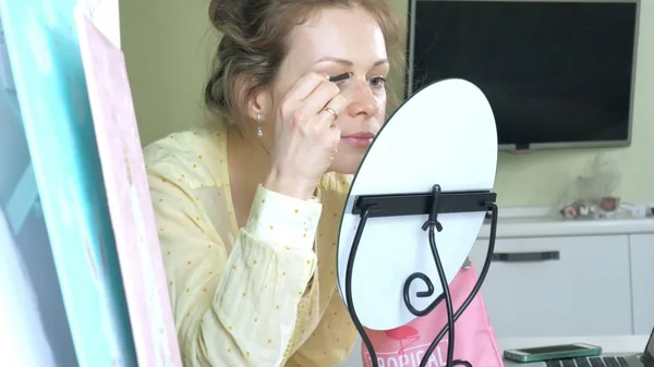 Young beautiful woman doing makeup in front of a mirror at home. — Stock Photo, Image