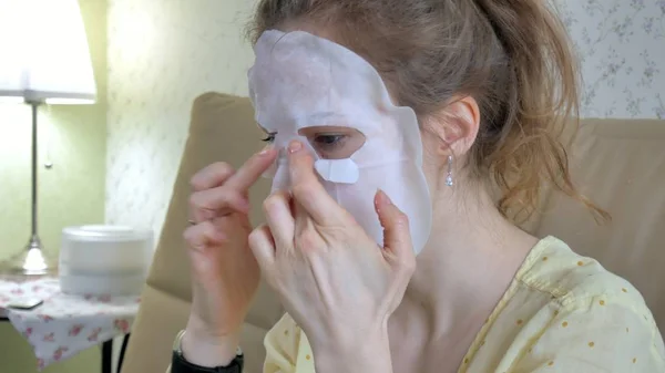 Mujer joven haciendo máscara facial con máscara de limpieza en la cara en la cocina en casa —  Fotos de Stock