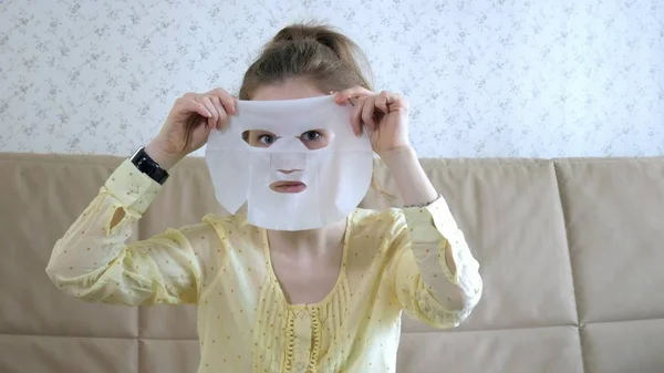 Молода жінка робить маску для обличчя з маскою для очищення обличчя на кухні вдома — стокове фото