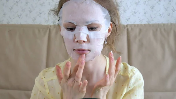 Молода жінка робить маску для обличчя з маскою для очищення обличчя на кухні вдома — стокове фото
