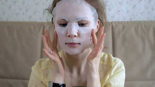 Jovem mulher fazendo máscara facial com máscara de limpeza no rosto na cozinha em casa — Fotografia de Stock