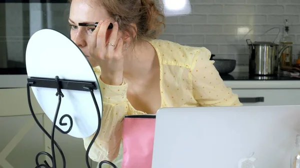 Joven hermosa mujer haciendo maquillaje delante de un espejo en casa . — Foto de Stock