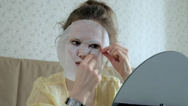 Mujer joven haciendo máscara facial con máscara de limpieza en la cara en la cocina en casa —  Fotos de Stock
