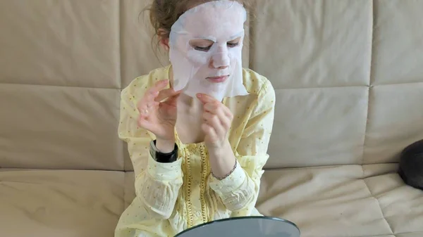 Mujer joven haciendo máscara facial con máscara de limpieza en la cara en la cocina en casa —  Fotos de Stock