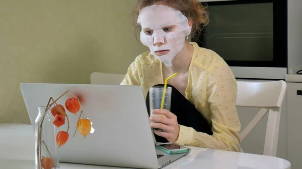 Junge Frau macht Gesichtsmaske mit Reinigungsmaske, arbeitet zu Hause hinter Laptop — Stockfoto