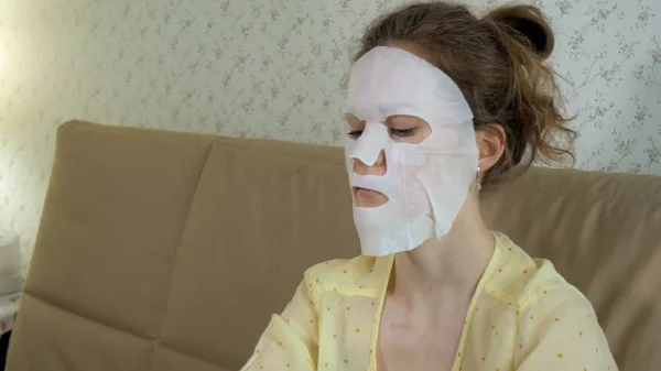 Jonge vrouw doet facial mask masker met zuivering masker op gezicht in keuken thuis — Stockfoto