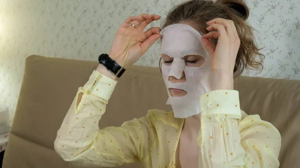 Jonge vrouw doet facial mask masker met zuivering masker op gezicht in keuken thuis — Stockfoto