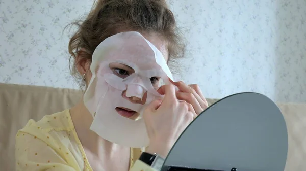 Giovane donna che fa maschera facciale con maschera detergente sul viso in cucina a casa — Foto Stock