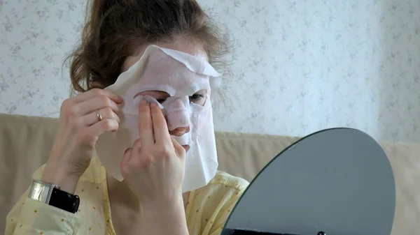 Mujer joven haciendo máscara facial con máscara de limpieza en la cara en la cocina en casa — Foto de Stock