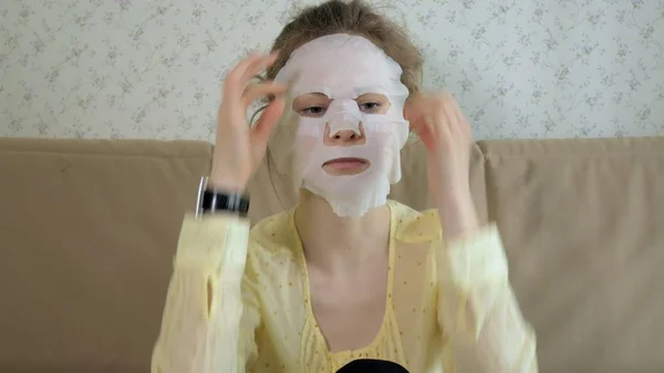 Ung kvinna gör ansiktsmask mask med rengörande mask på ansikte i köket hemma — Stockfoto