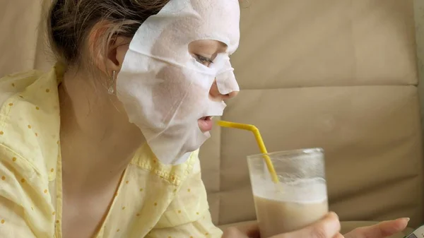 Wanita muda melakukan masker wajah dengan topeng pembersihan, bekerja di belakang laptop di rumah — Stok Foto