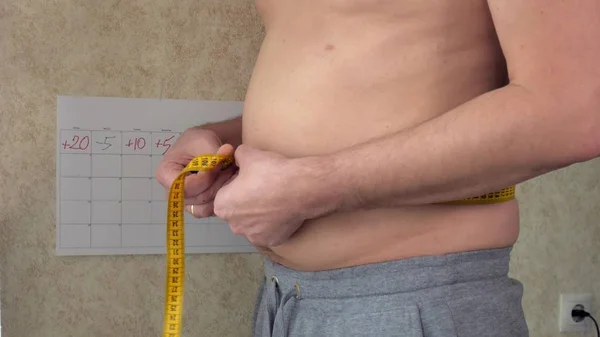 Толстяк измеряет свою талию, большой пивной живот, здоровый образ жизни — стоковое фото