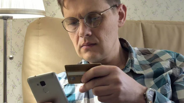 Γκρο πλαν ενός ανθρώπου που αγοράζουν σε απευθείας σύνδεση χρησιμοποιεί ένα τηλέφωνο και μια πιστωτική κάρτα στον καναπέ στο σπίτι ψώνια κινητό πελάτη closeup συσκευή χειρός lifestyle έξυπνες επιχειρηματικές internet τεχνολογία Τράπεζα τραπεζικό χρήμα εκμετάλλευση — Φωτογραφία Αρχείου