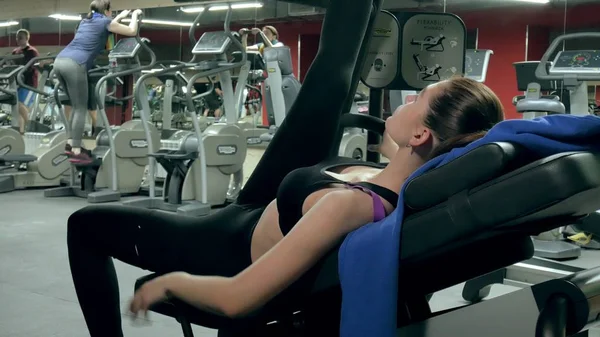Een aantrekkelijke vrouw doet zich uitstrekt op een simulator in een sportschool sport — Stockfoto