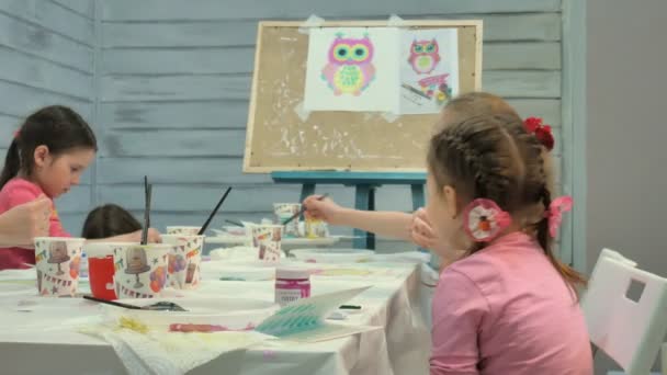 Niños niños y niñas sentados juntos alrededor de la mesa en el aula y dibujando . — Vídeos de Stock