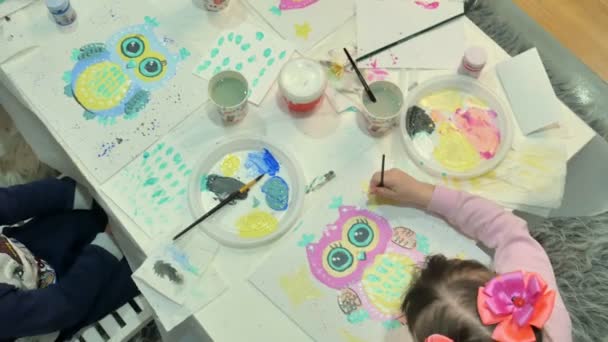 Niños niños y niñas sentados juntos alrededor de la mesa en el aula y dibujando . — Vídeo de stock