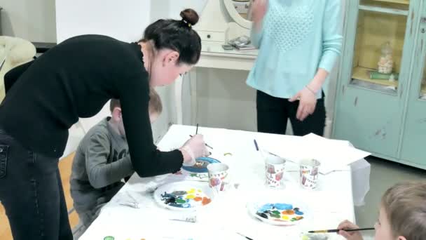 Kinderen-jongens zitten samen rond de tafel in de klas en tekening. Met hen is hun jong en mooi leraar. — Stockvideo