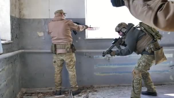 Soldiers in camouflage with a military weapon aiming through the rifle sight through the window of an old building, the military concept — Stock Video