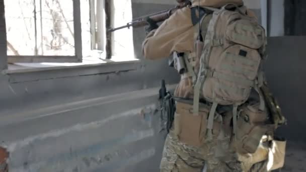 Soldiers in camouflage with a military weapon aiming through the rifle sight through the window of an old building, the military concept — Stock Video