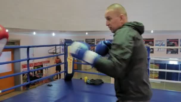 De trainer voert een strijd van de opleiding met een vrouwelijke kickboxer in de ring — Stockvideo