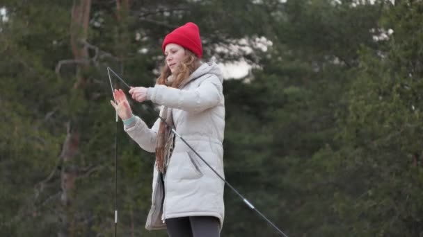 Turisticky mladá žena v červeném klobouku shromažďuje turistický stan poblíž lesa na pobřeží — Stock video