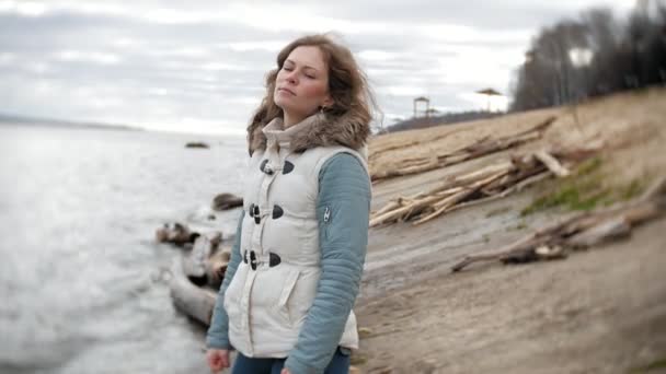 Beautiful young woman walking along the river bank and collecting dry branches — Stock Video