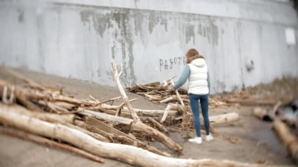 Mooie jonge vrouw lopen langs de rivieroever en het verzamelen van droge takken — Stockvideo