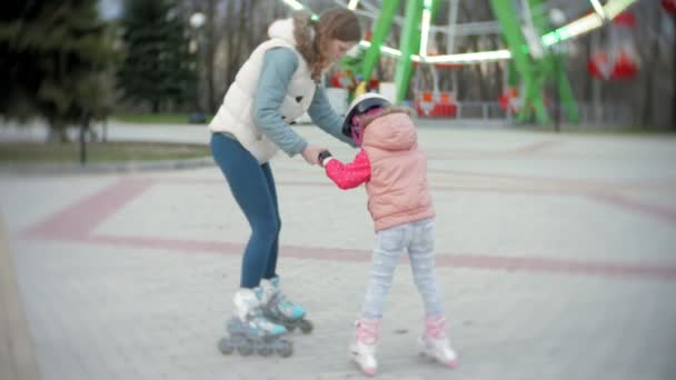 Mamá y su hija montan patines. Chica aprendiendo a patinar, y cae. Mamá enseña a su hija a montar en rodillos — Vídeos de Stock