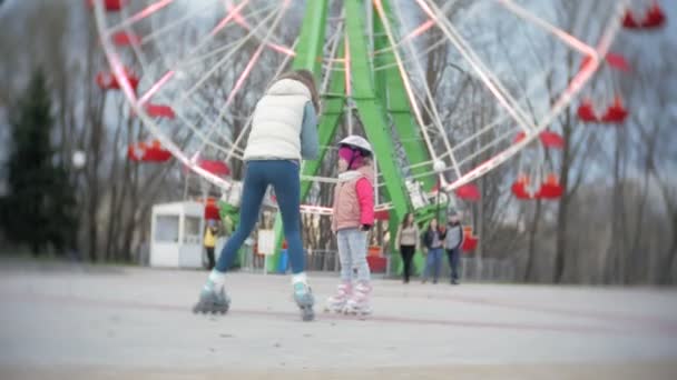 妈妈和女儿骑在旱冰鞋上。女孩学习轮滑，和瀑布。妈妈教女儿骑辊 — 图库视频影像