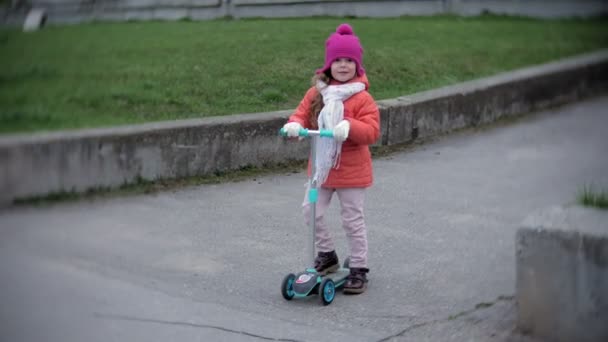 Klein meisje in de helm een kick scooter rijden — Stockvideo