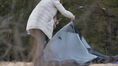 Çekici genç turist kadın kırmızı şapkalı bir turist çadır forest yakınındaki sahil üzerinde toplar.
