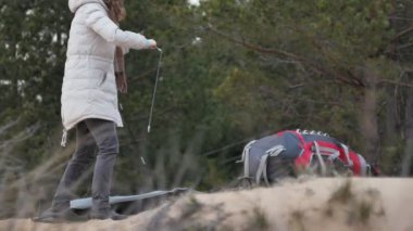 Çekici genç turist kadın kırmızı şapkalı bir turist çadır forest yakınındaki sahil üzerinde toplar.