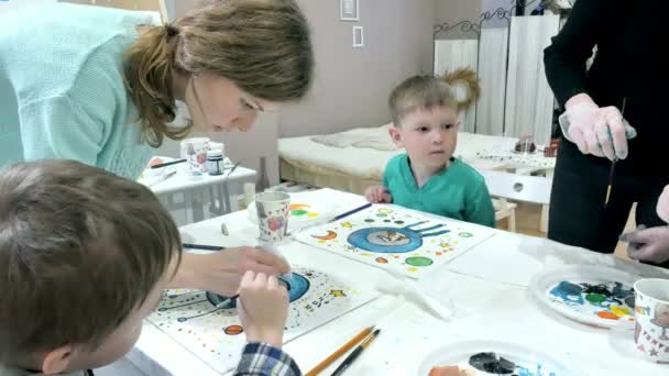 Kinderen-jongens zitten samen rond de tafel in de klas en tekening. Met hen is hun jong en mooi leraar. — Stockvideo