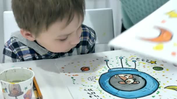 Bambini ragazzi seduti insieme intorno al tavolo in classe e disegno. Con loro c'è la loro giovane e bella maestra . — Video Stock