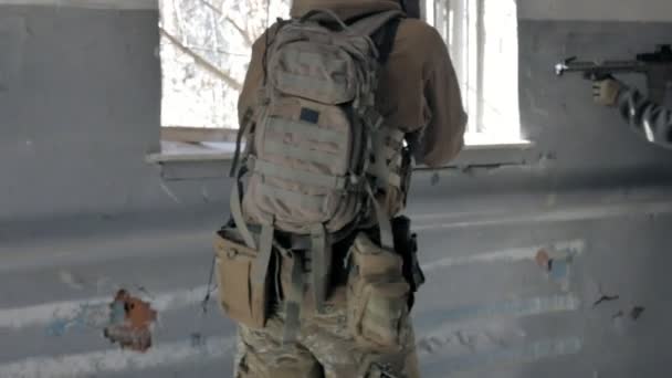 Soldiers in camouflage with a military weapon aiming through the rifle sight through the window of an old building, the military concept — Stock Video