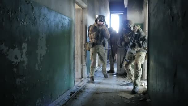 Soldados en camuflaje con armas de combate se escabullen por los pasillos del antiguo edificio, el concepto militar — Vídeo de stock