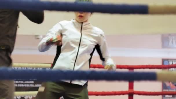 El entrenador lleva a cabo una batalla de entrenamiento con una kickboxer femenina en el ring — Vídeo de stock