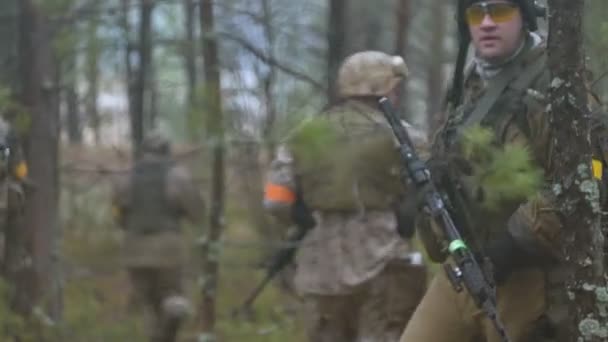 Солдаты в камуфляже с боевым оружием выходят за пределы леса, с целью захватить его, военная концепция — стоковое видео