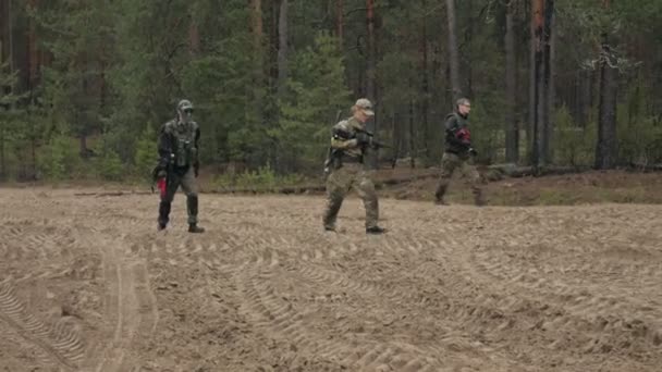 Des soldats en camouflage avec des armes de combat font leur chemin hors de la forêt, dans le but de la capturer, le concept militaire — Video