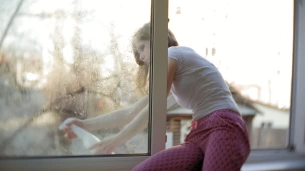 Приваблива дівчина миє вікна вдома. Щоб прибрати будинок . — стокове відео