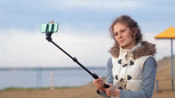 Söt flicka leende ta själv föreställer selfie med smart telefon mobil på Älvstranden — Stockvideo