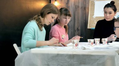Çocuk erkek ve kız birlikte sınıf ve çizim masasının etrafında oturuyor. Onlarla birlikte onların genç ve güzel bir öğretmendir. 4k